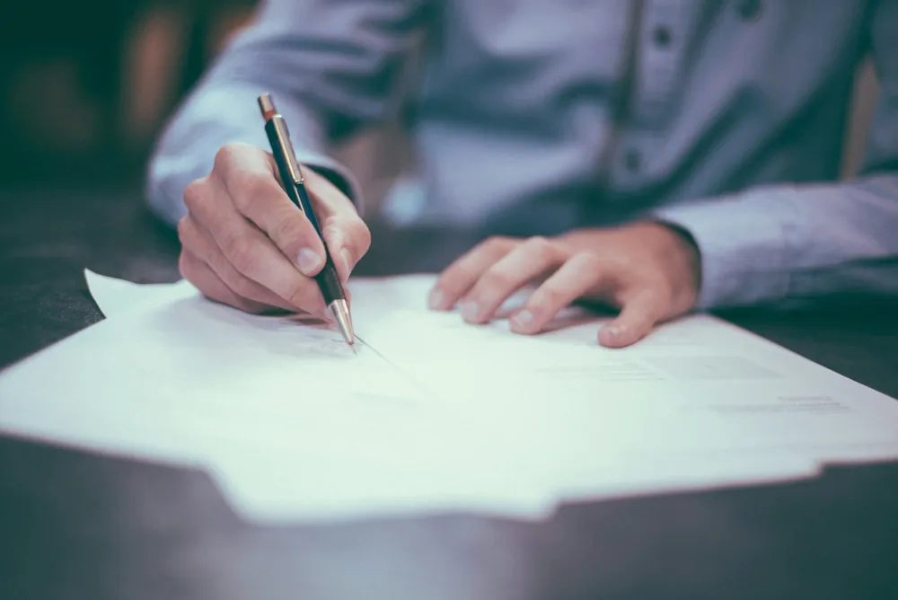 Mano che firma un documento con una penna
